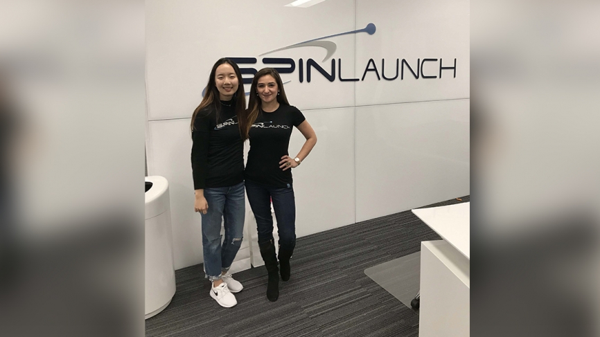 两个女人站在品牌前说“SpinLaunch。”