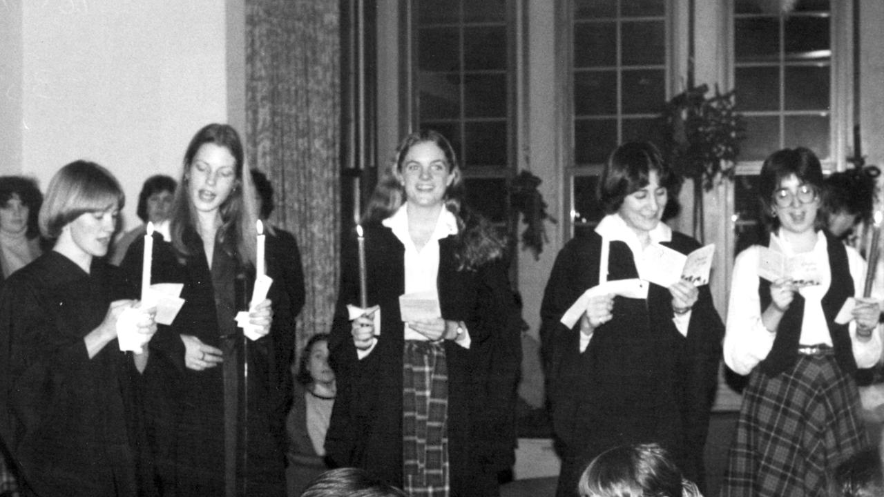 复古照片从1980年显示学生拿着蜡烛,唱着度假。