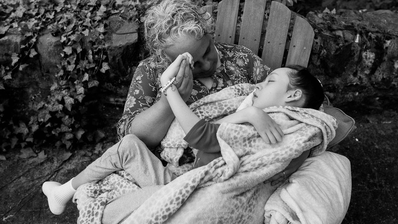 A photo of Maria Kefalas sitting in a chair with her daughter Cal on her lap.