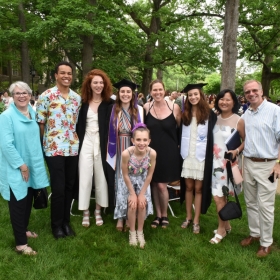 一张照片显示了两个骄傲的家庭成员thered with their graduates on the lawn after Commencement.