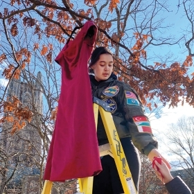 一张照片显示，美国国家航空航天局（NASA）总裁，切诺基印第安人东部乐队的后代艾玛·斯莱贝克（Emma Slibeck ’24），作为补救装置的一部分，从学术四轮的一棵树上悬挂了一条红色连衣裙。