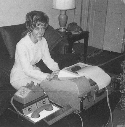 Old photo of a young Betsy Knapp sitting on a couch at an old fashioned terminal