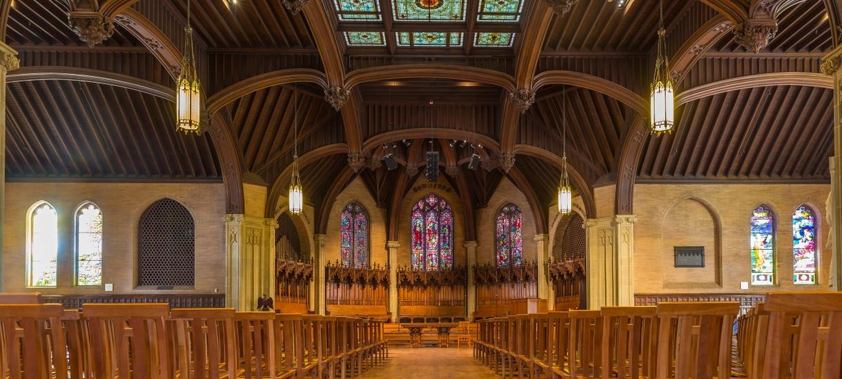 Empty interior of Houghton Chapel with wooden pews and stained glass windows