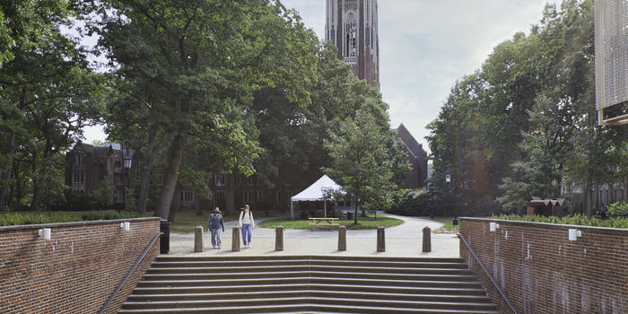 亚博永久官网韦尔斯利学院的盖伦石头塔朱厄特大厅的台阶的前景和两个学生走路。