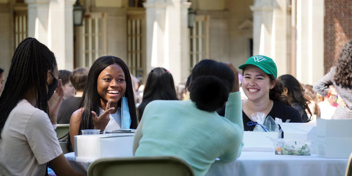 students smiling and eating together at an outdoor table