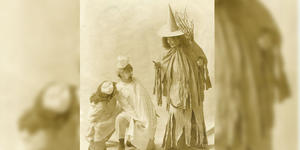A theater photo from 1906 showing three students re-enacting a scene. The student at right is dressed as a witch.