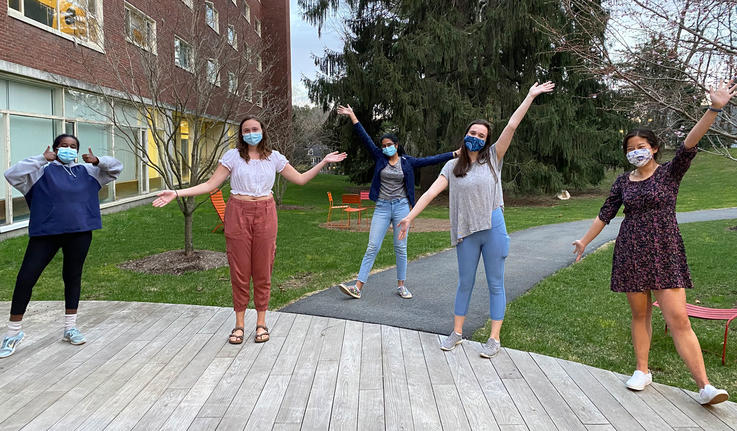 people wearing masks and posing with their hands up in the air