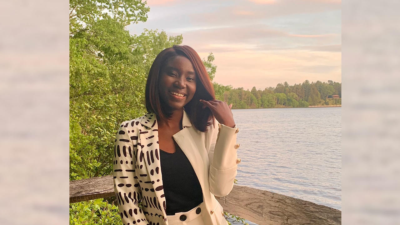 Adwoa Difie Antwi'21posing in front of Lake Waban with a sunset sky